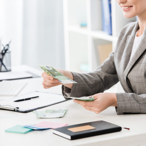 cropped image of businesswoman counting euro banknotes at table in office